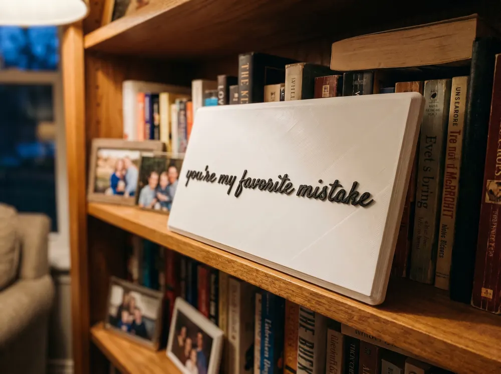 A 3D-printed Thudletter slab with raised handwritten lettering reading 'you're my favorite mistake', shown in a real home setting.